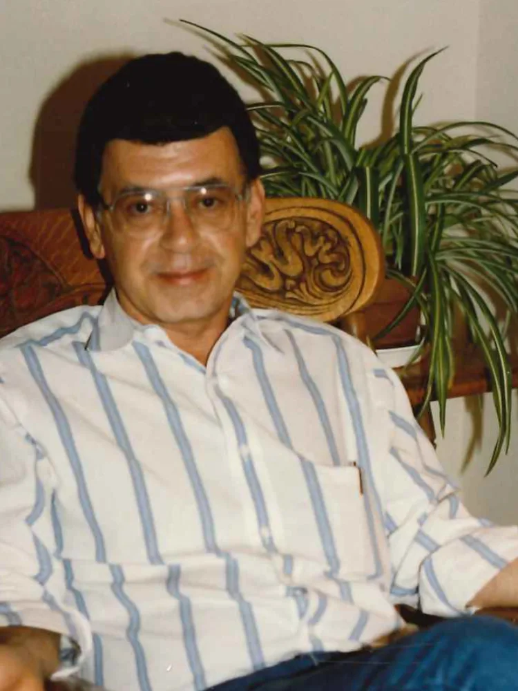 Doug Nassif in his earlier years, seated in a carved wooden chair